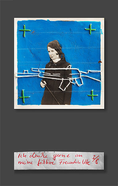 Ute vor einer blauen Wand mit grünen Kreuzen und einem gestickten Maschinengewehr. Bildunterschrift: Ich denke gerne an meine fiktive Freundin Ute.